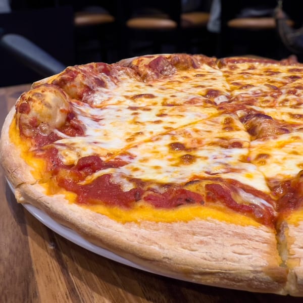 A close-up of a freshly baked cheese pizza with tomato sauce, sliced and ready to eat.