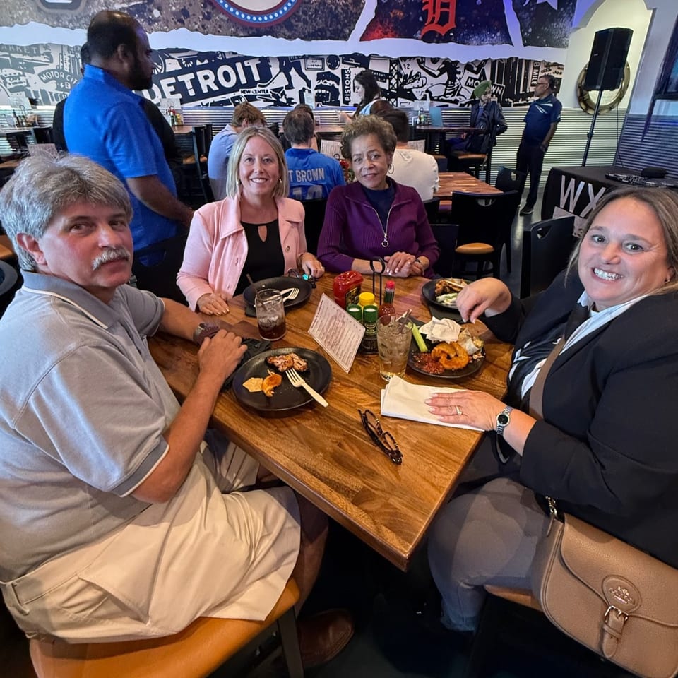 Four patrons enjoying food and drinks at a wooden table in O Grizzly's Bar & Bistro.