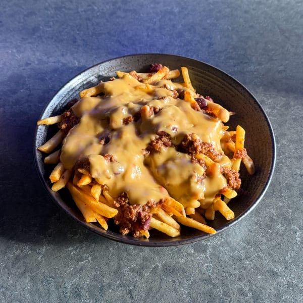 O Grizzly's Bar & Bistro's chili cheese fries, a dark bowl filled with golden fries, chili, and cheese sauce.