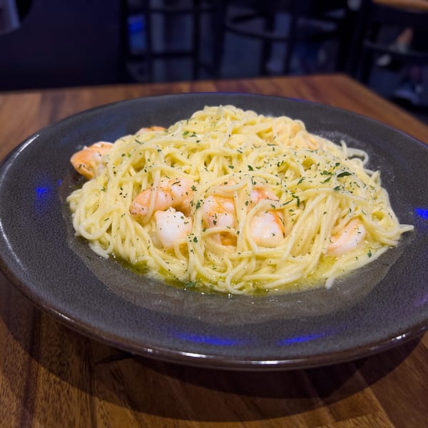 Spaghetti with shrimp and parsley in a light sauce, served on a dark plate at O Grizzly's Bar & Bistro.